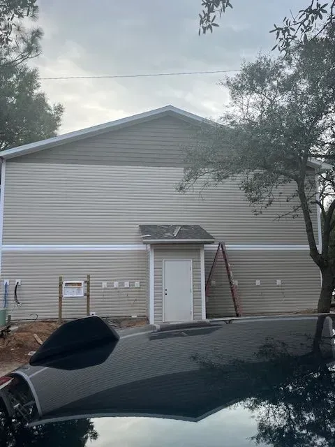 A black car is parked in front of a house under construction.