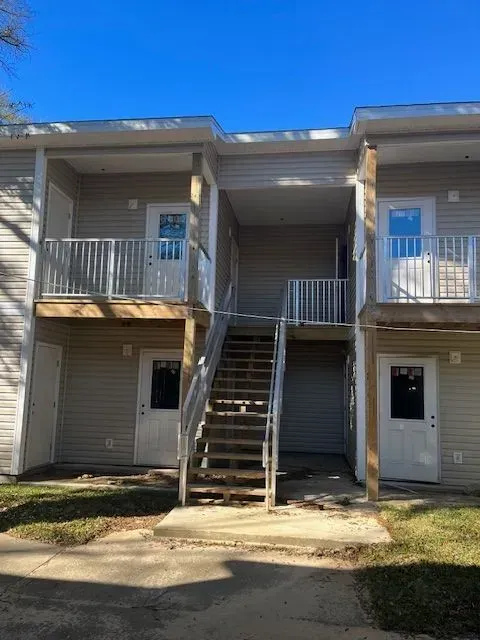 A large apartment building with stairs leading up to the second floor.