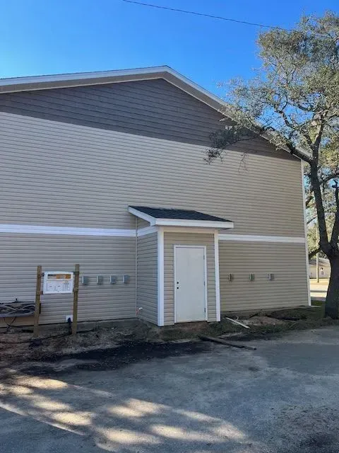 A large building with a white door and a tree in front of it.