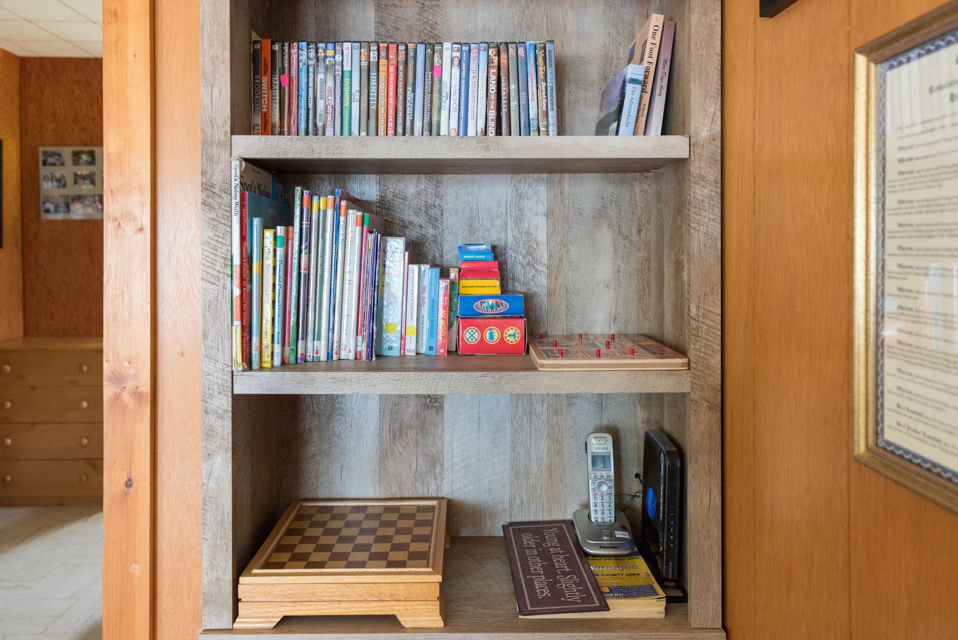 Built-in wooden bookshelf with books, magazines, and small items in a hallway nook