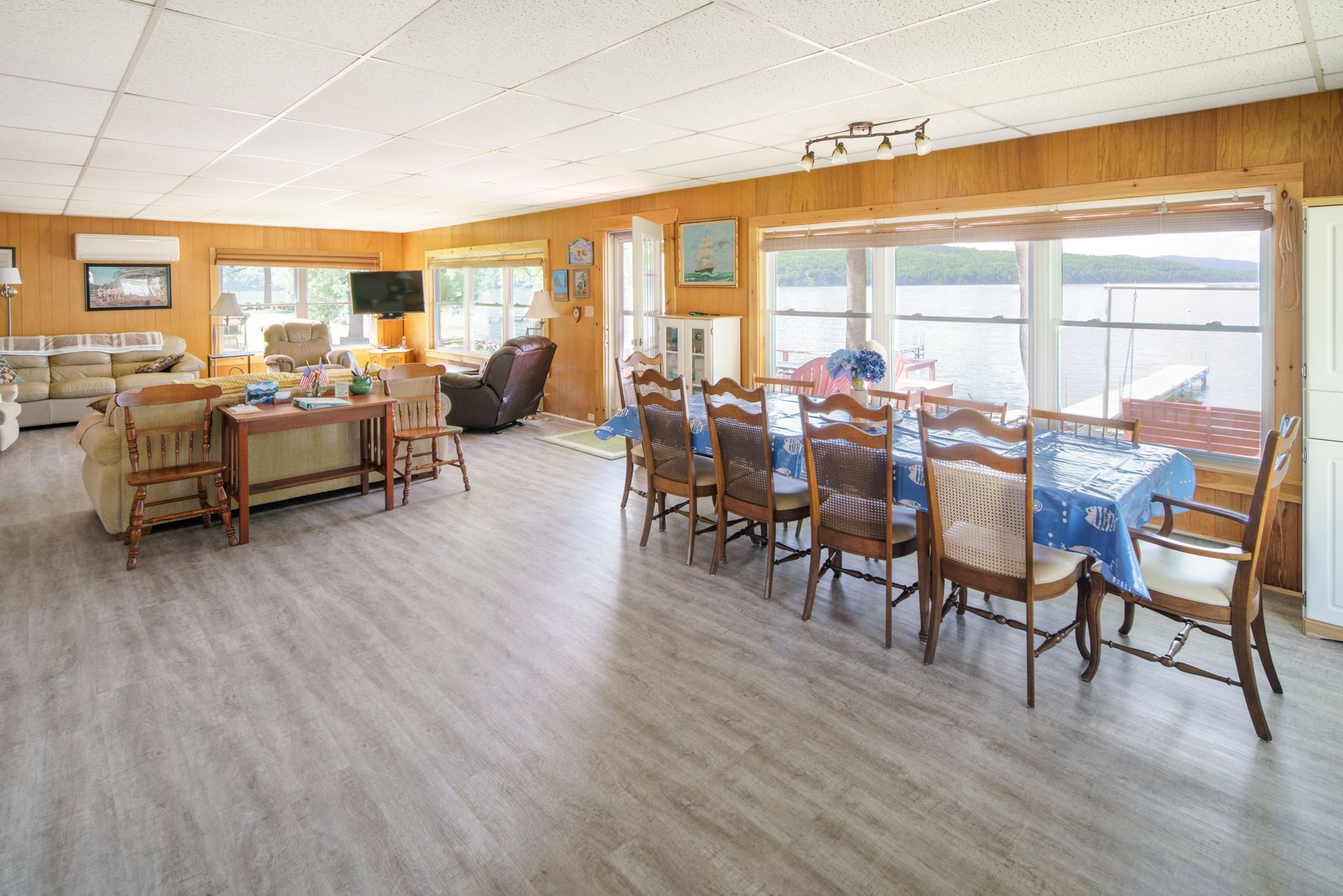 Bright dining room with long table, wooden chairs, couches, and large windows overlooking a bright view