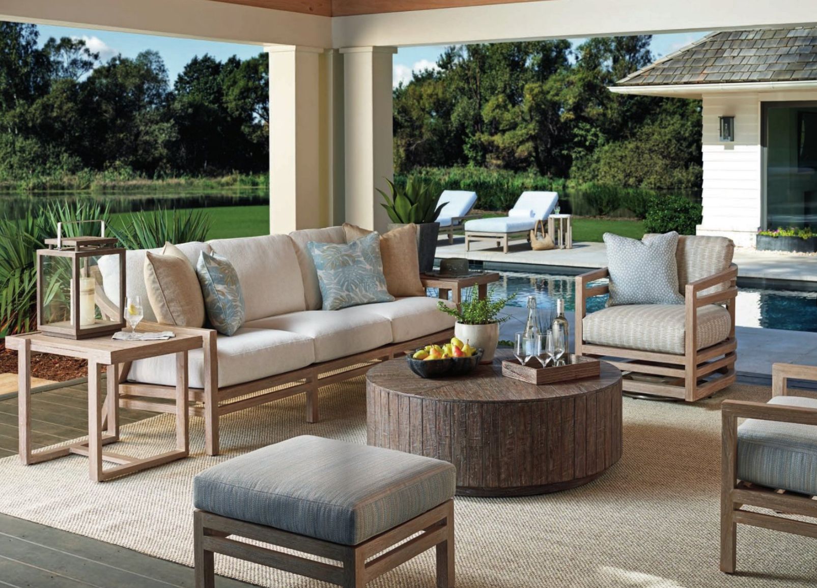 An outdoor living room with a couch, chairs, coffee table and ottoman.