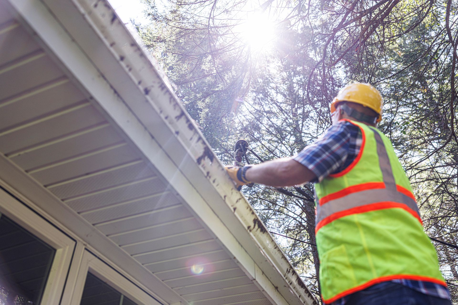A man is working on a gutter on the side of a house