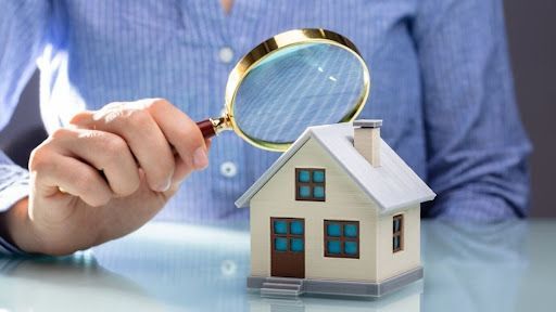 A person is looking at a model house through a magnifying glass