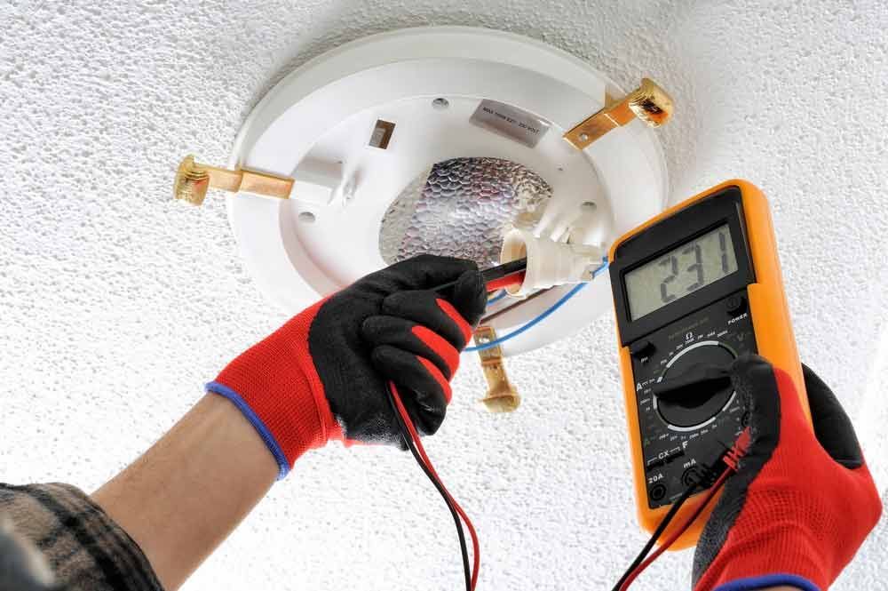 Electrician Measuring The Voltage In The Lamp Socket