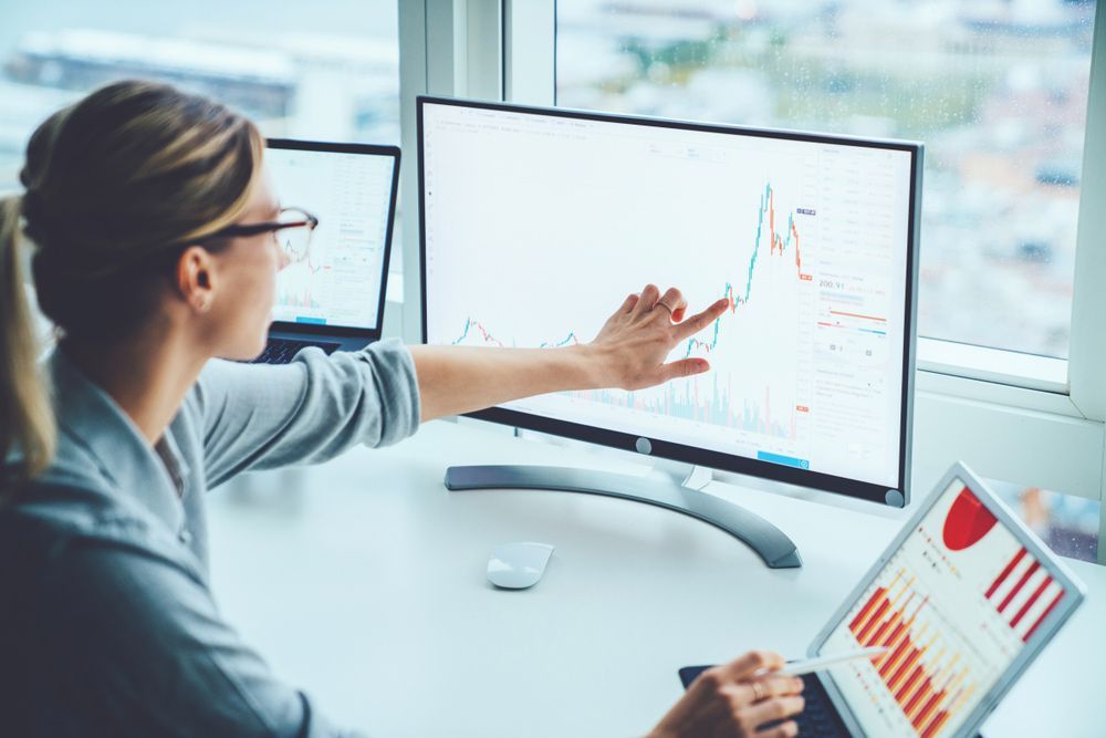 A Woman Is Sitting At A Desk Looking At A Computer Screen — NQ Business Advisers In Jensen, QLD