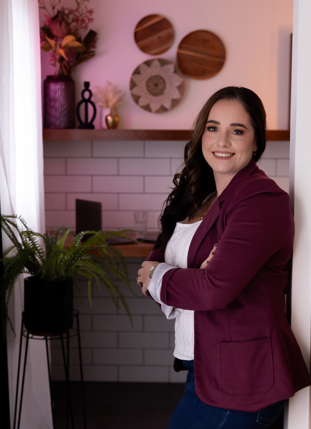 A Woman Standing In The Doorway Smiling And Wearing A Moroon Blazer — NQ Business Advisers In Jensen, QLD