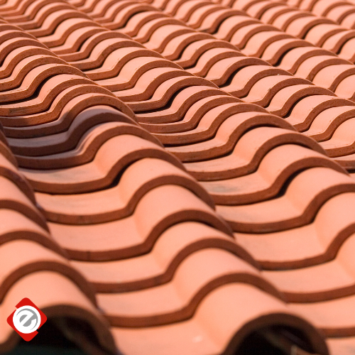 Close-up of a terracotta tile roof with curved tiles, warm reddish-brown color.