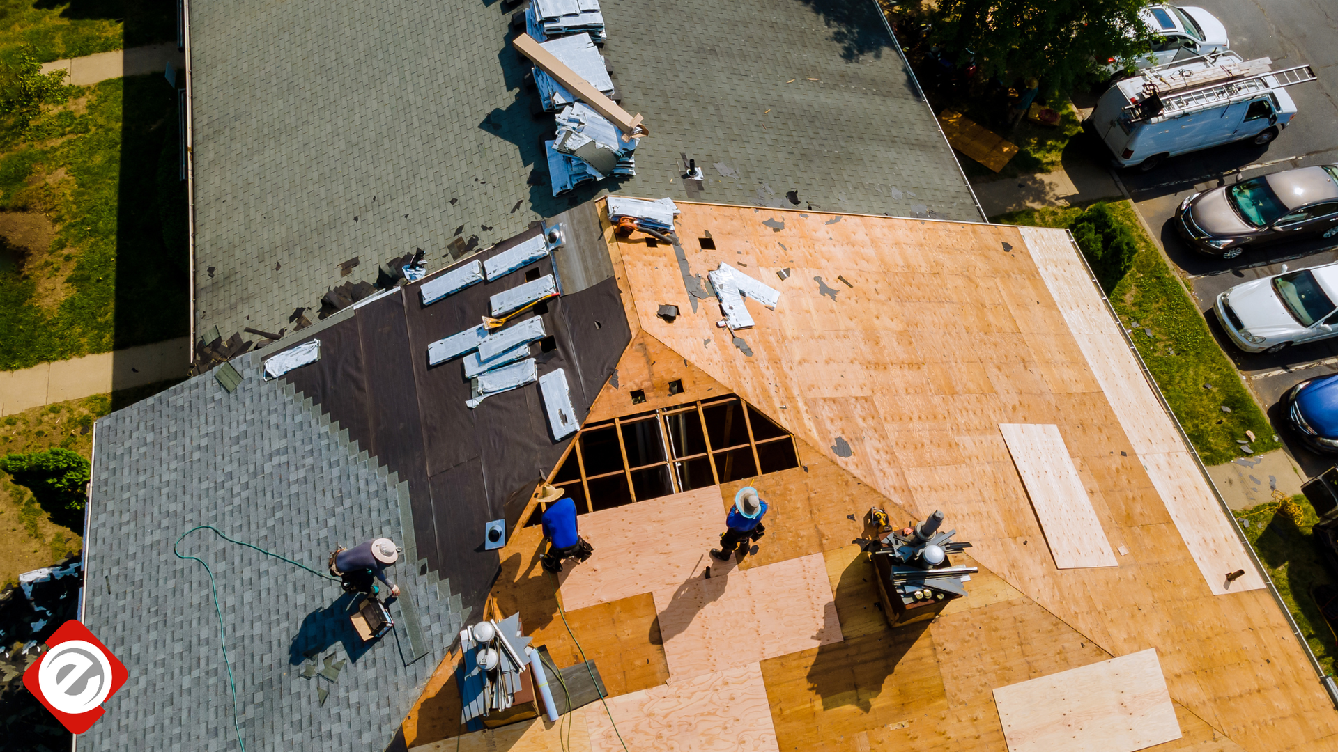 Roofers working on a house roof. One section has shingles, another has plywood. Cars parked in background.