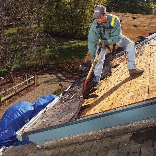 A man is working on the roof of a house with a shovel.