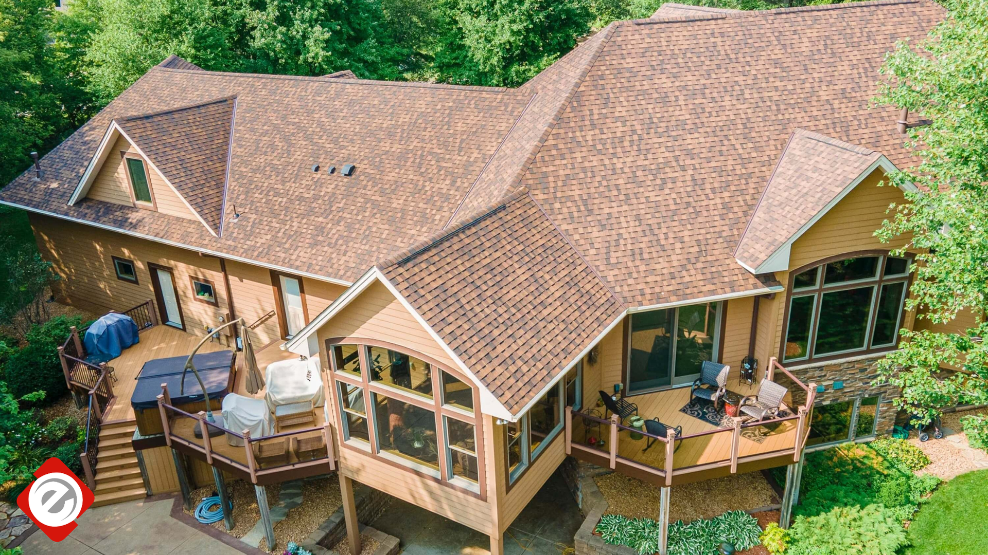 Brown-roofed house with multiple decks, surrounded by trees, sunny day.