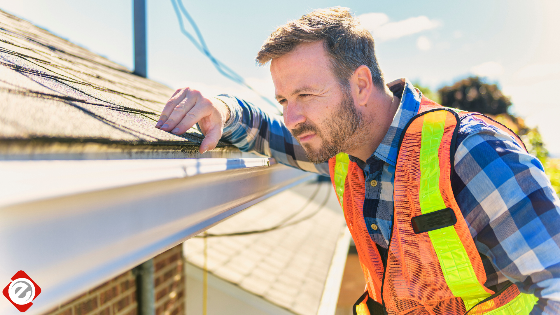 Man in safety vest examines gutter on a roof.