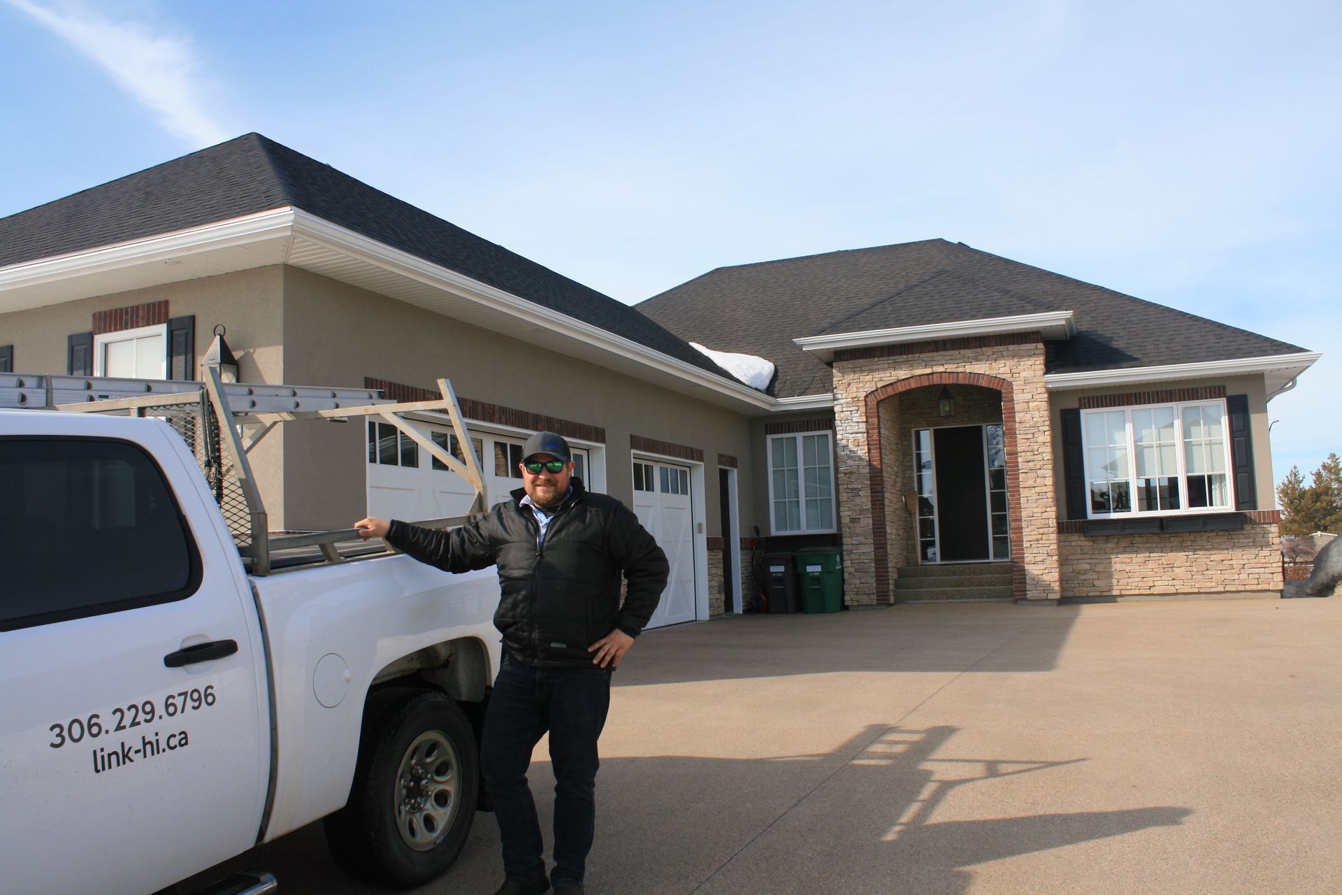 A man is standing next to a white truck in front of a house.