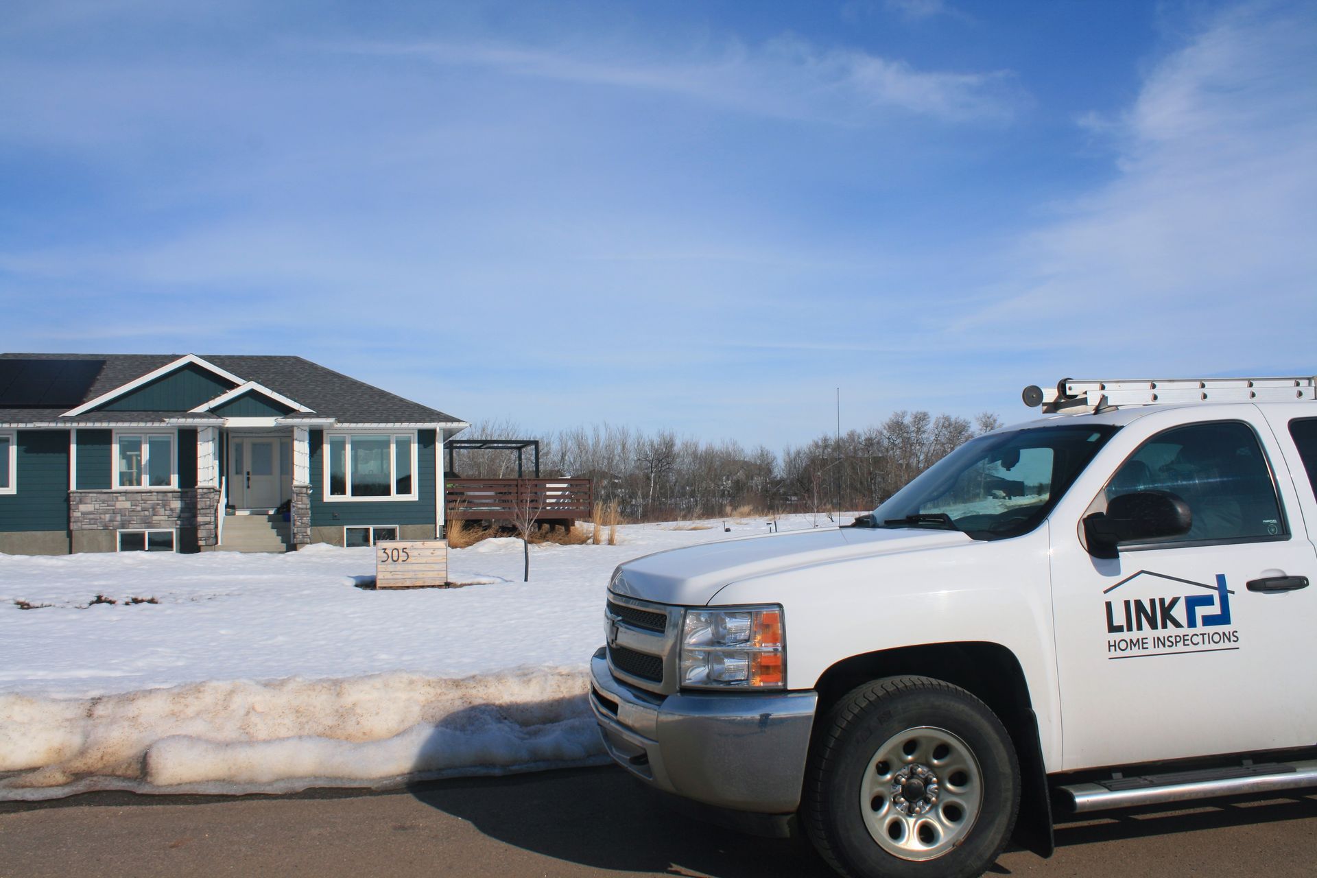 A white truck with the word link on it is parked in front of a house