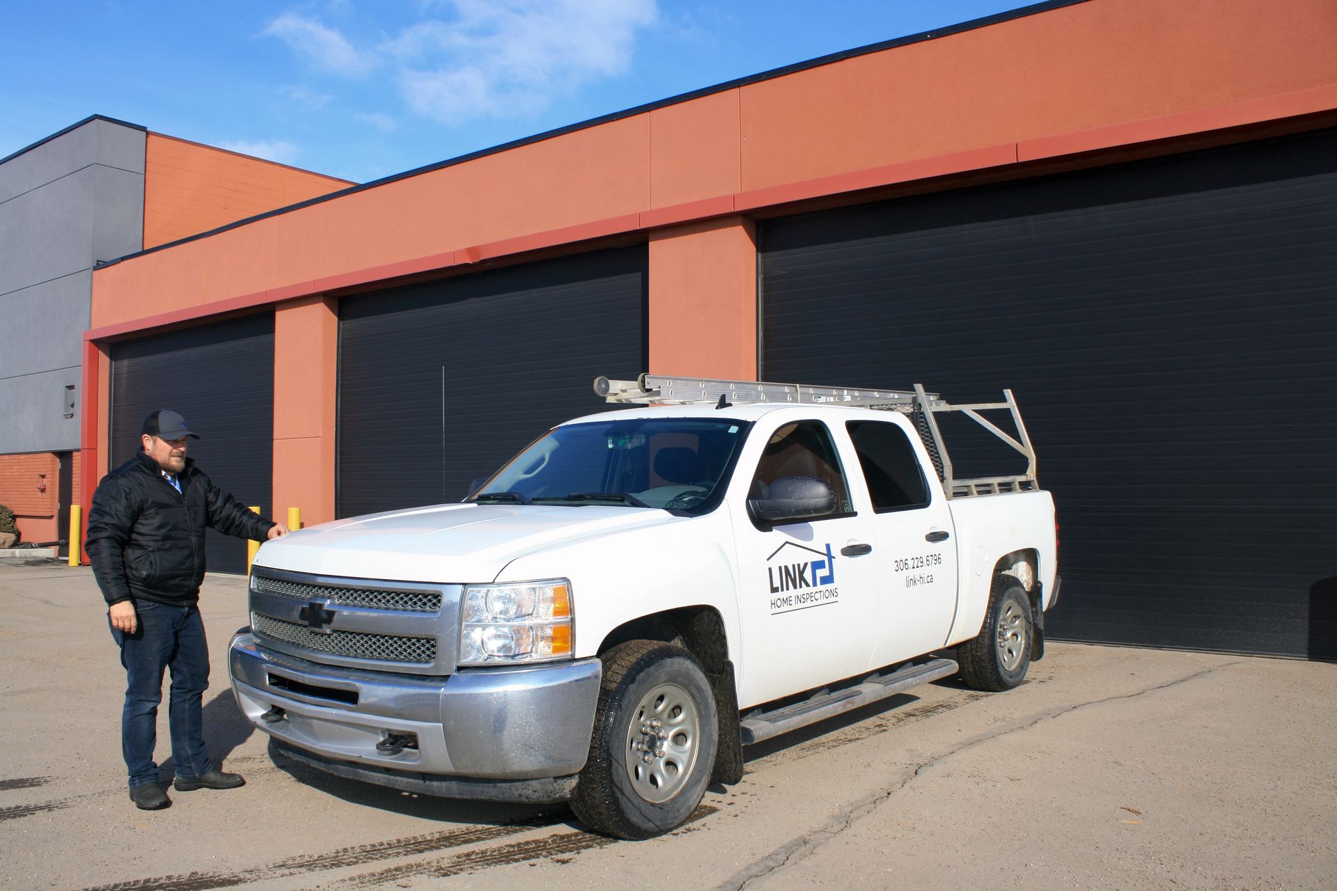 A man is standing next to a white truck in front of a building.
