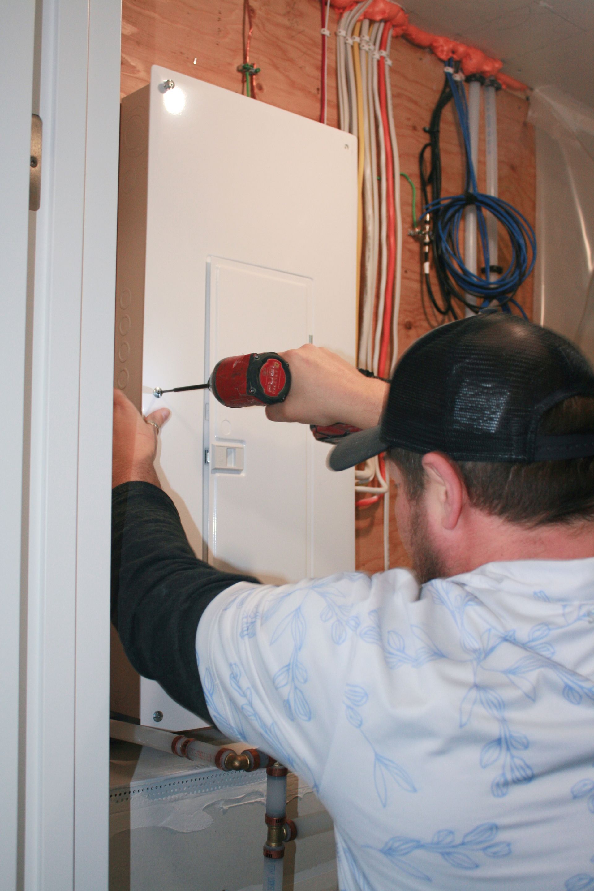 A man is using a screwdriver to fix an electrical box