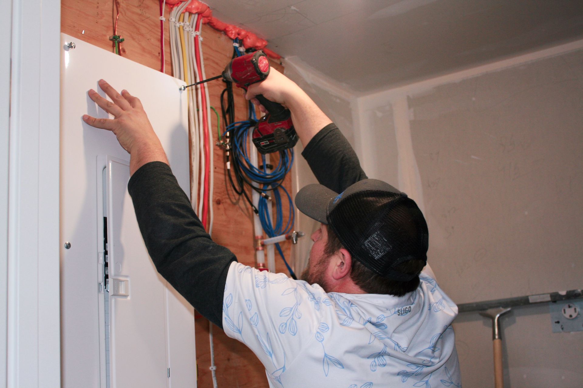 A man is working on a wall with a drill.