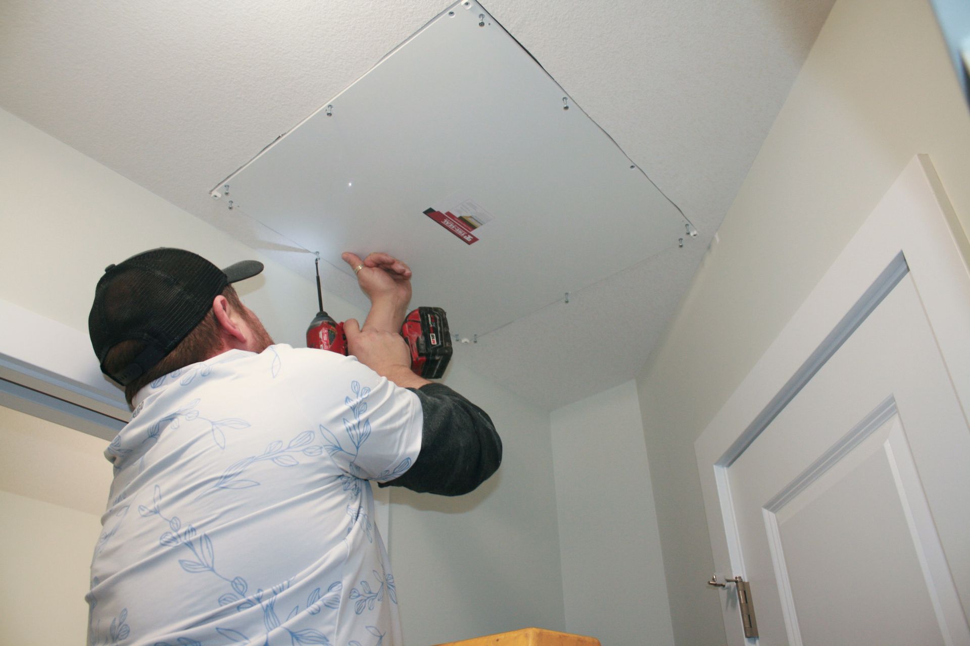 A man is working on a ceiling with a drill.