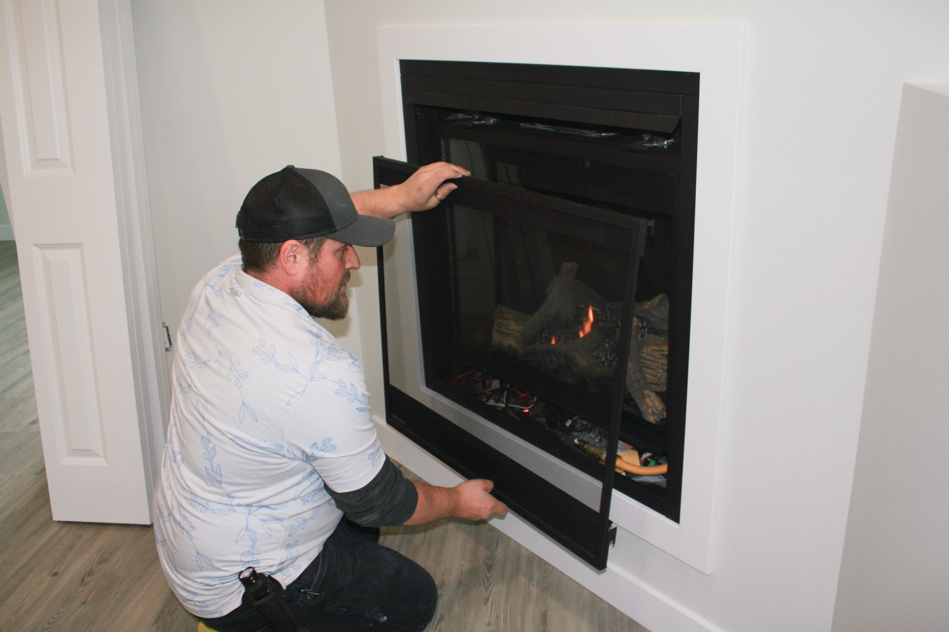 A man is installing a fireplace in a living room.
