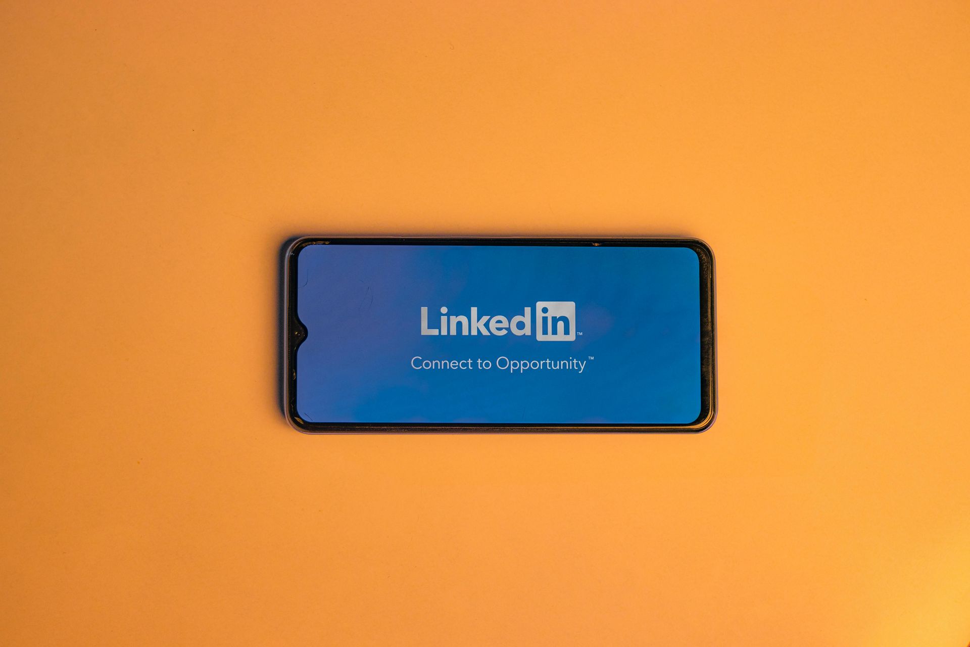 Phone with LinkedIn open against orange background