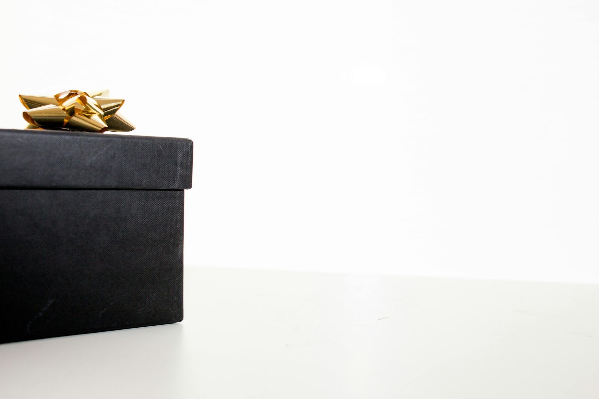 black box with a gold bow against white background