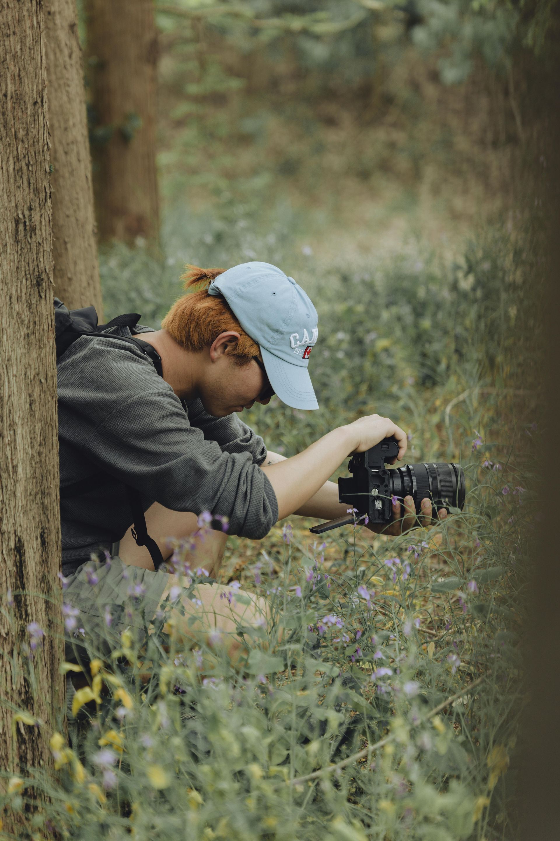 Red headed guy with a baseball cap taking a picture in the field