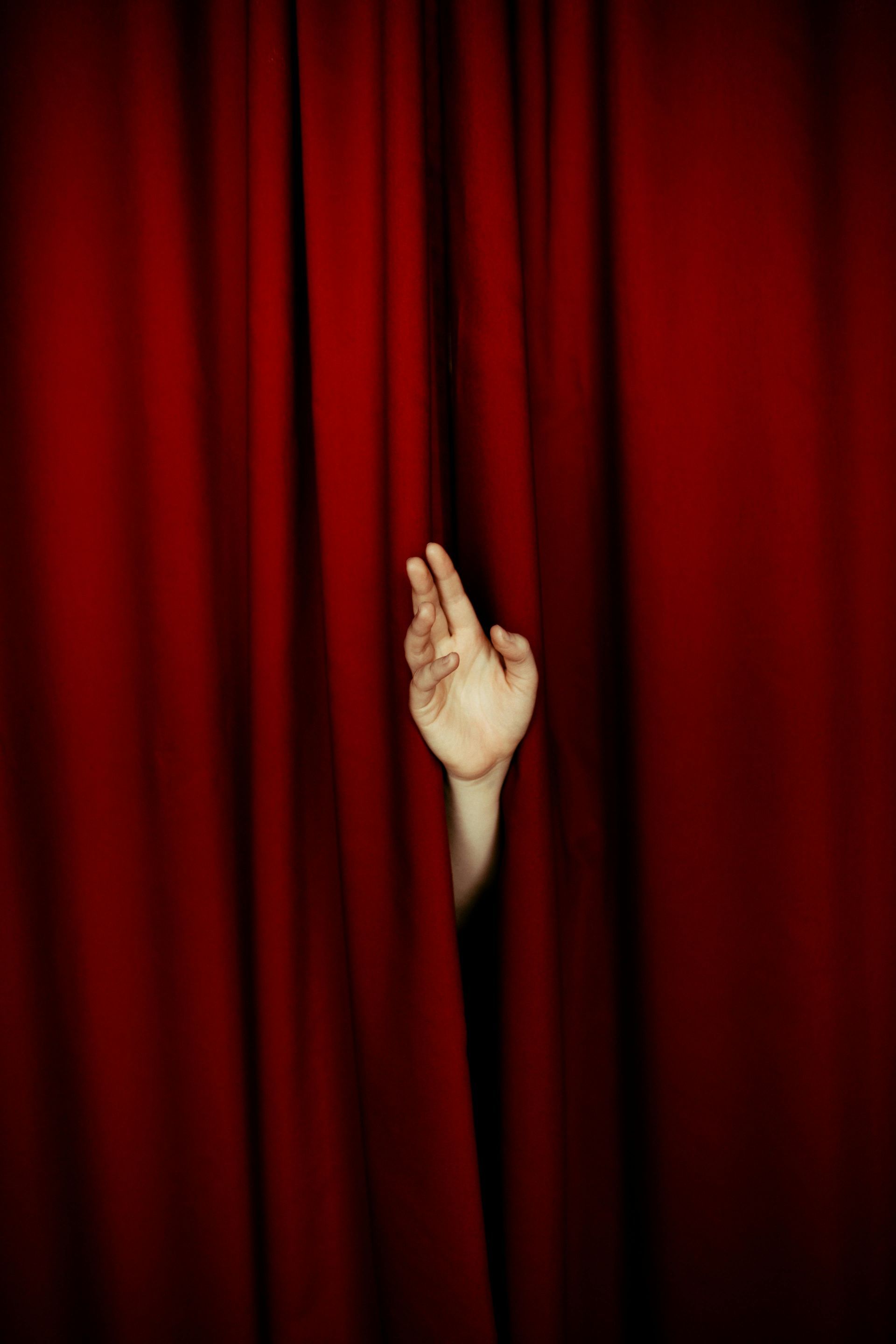 hand coming out of a red curtain