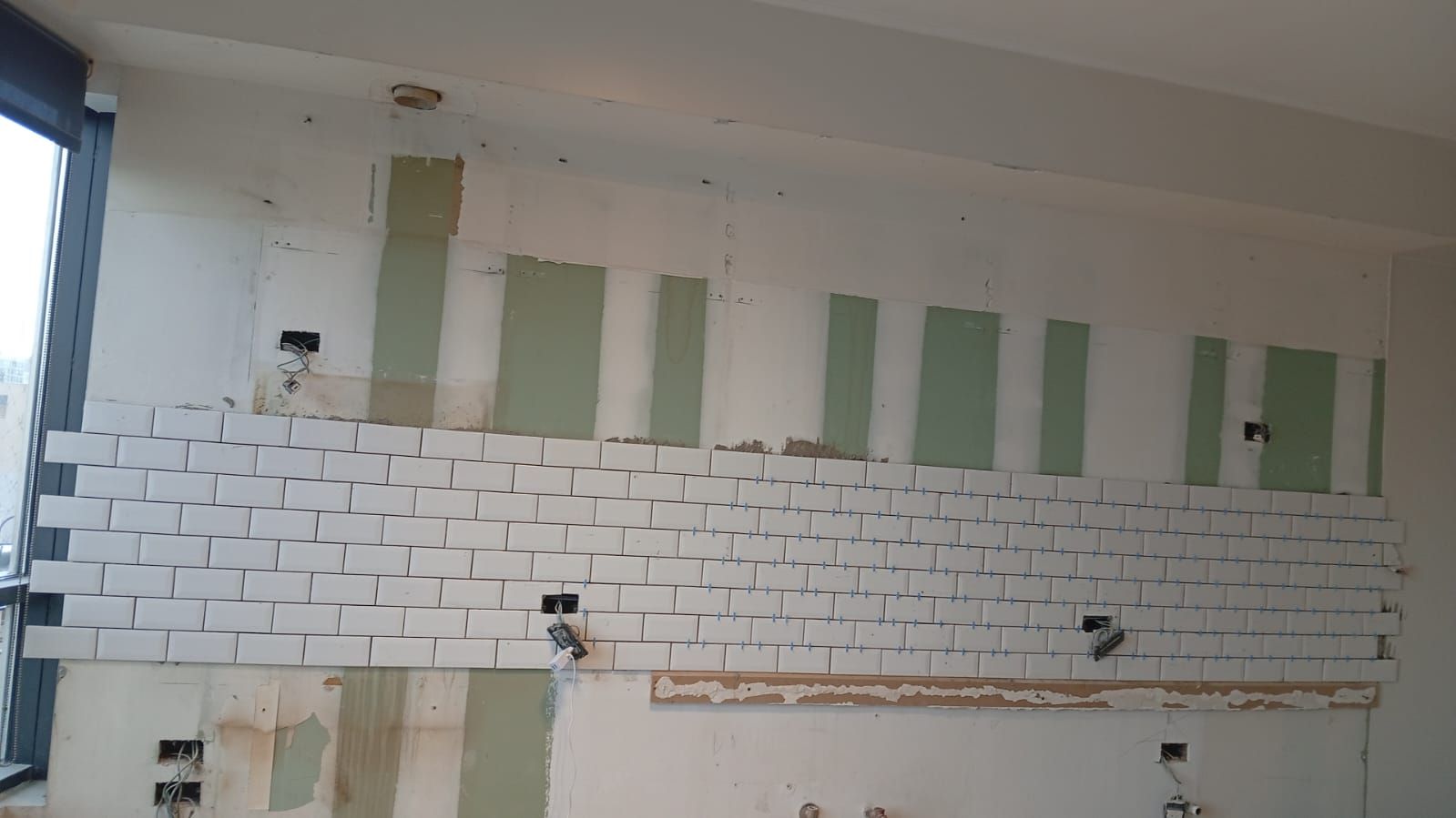 Hilera de edificios sin terminar con andamios contra el exterior de estuco; sitio de construcción.