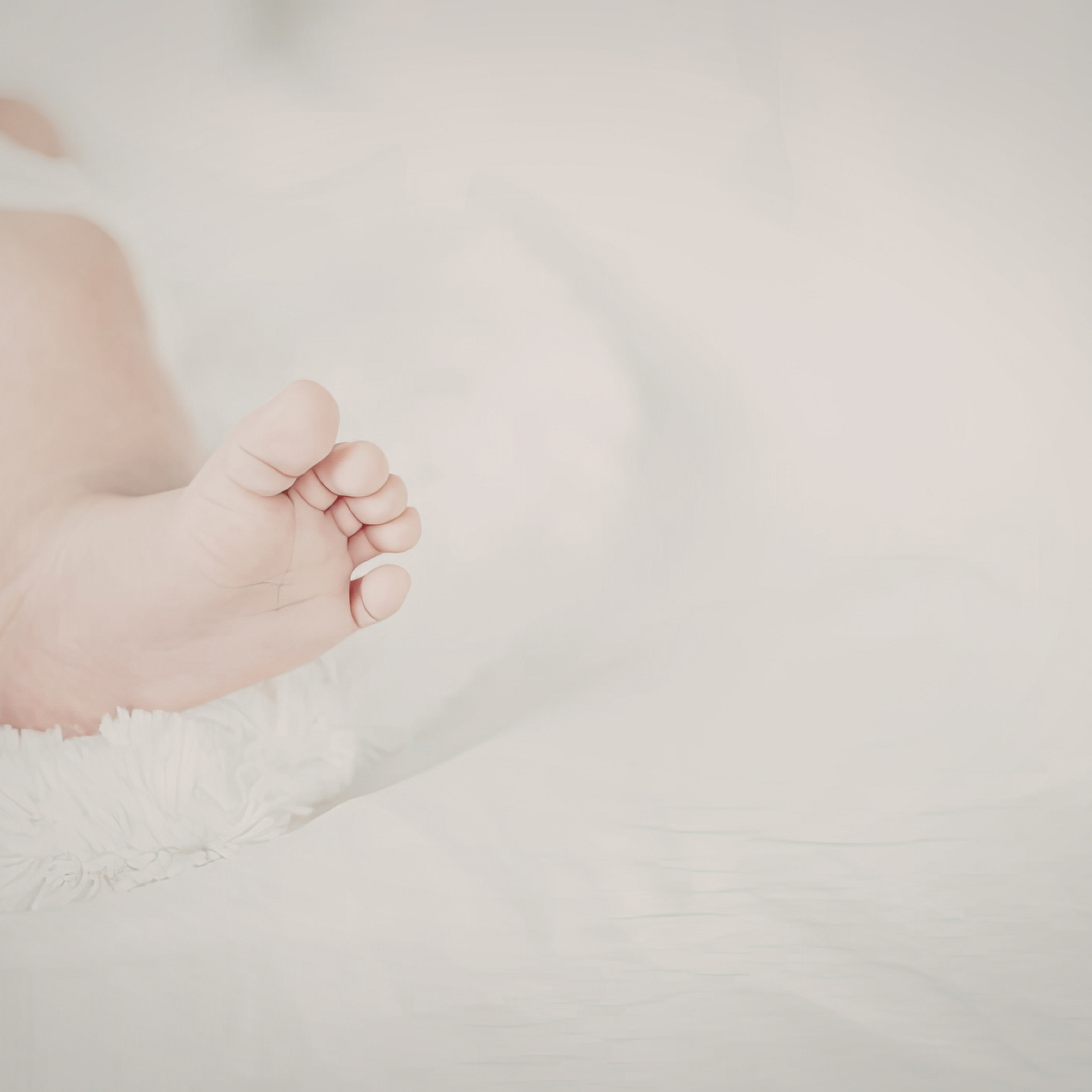 A close-up of a small foot resting on a soft, white textured surface.