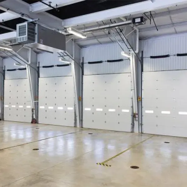 White garage doors in an industrial setting, with a polished floor and overhead lights.