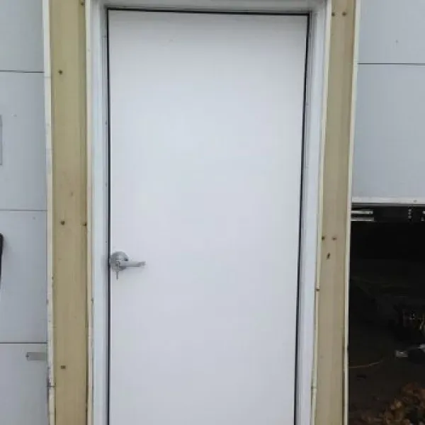 White door with silver handle in a building, brown frame around it.