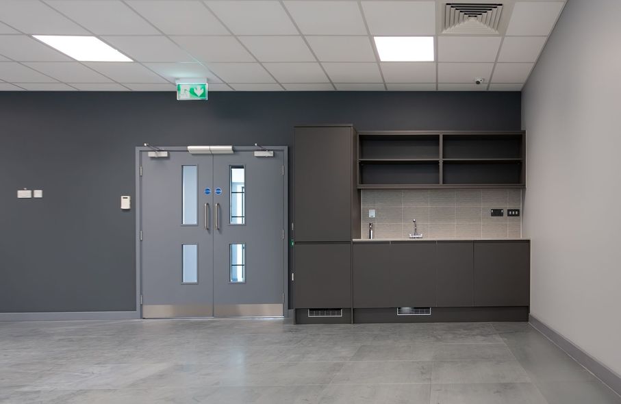 Empty room with gray cabinets, double doors, and a concrete floor.
