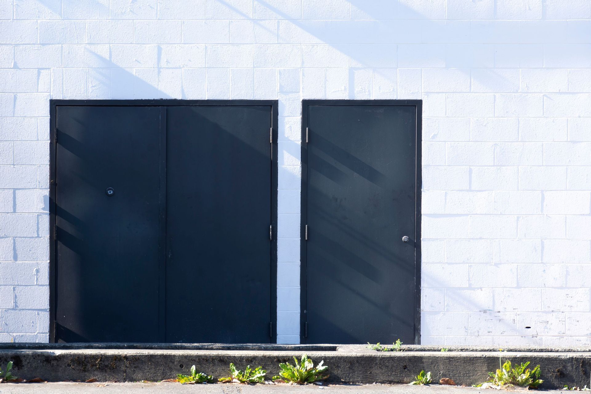 Two black doors in white brick wall.