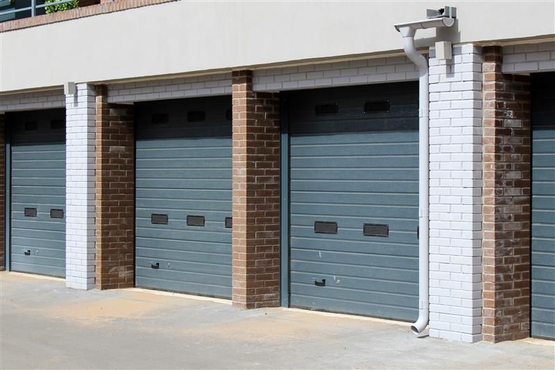 Gray garage doors with brown brick and white pillars.