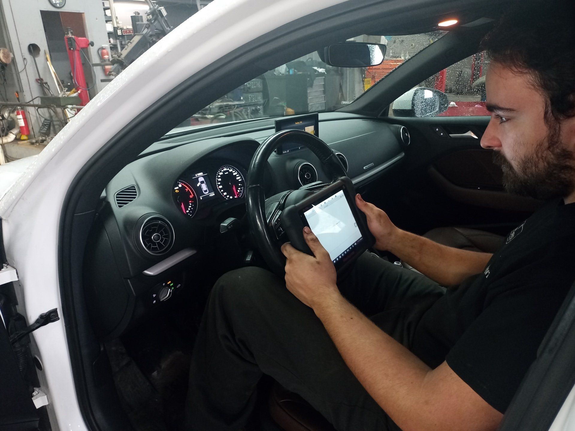 Un homme est assis dans une voiture en utilisant une tablette