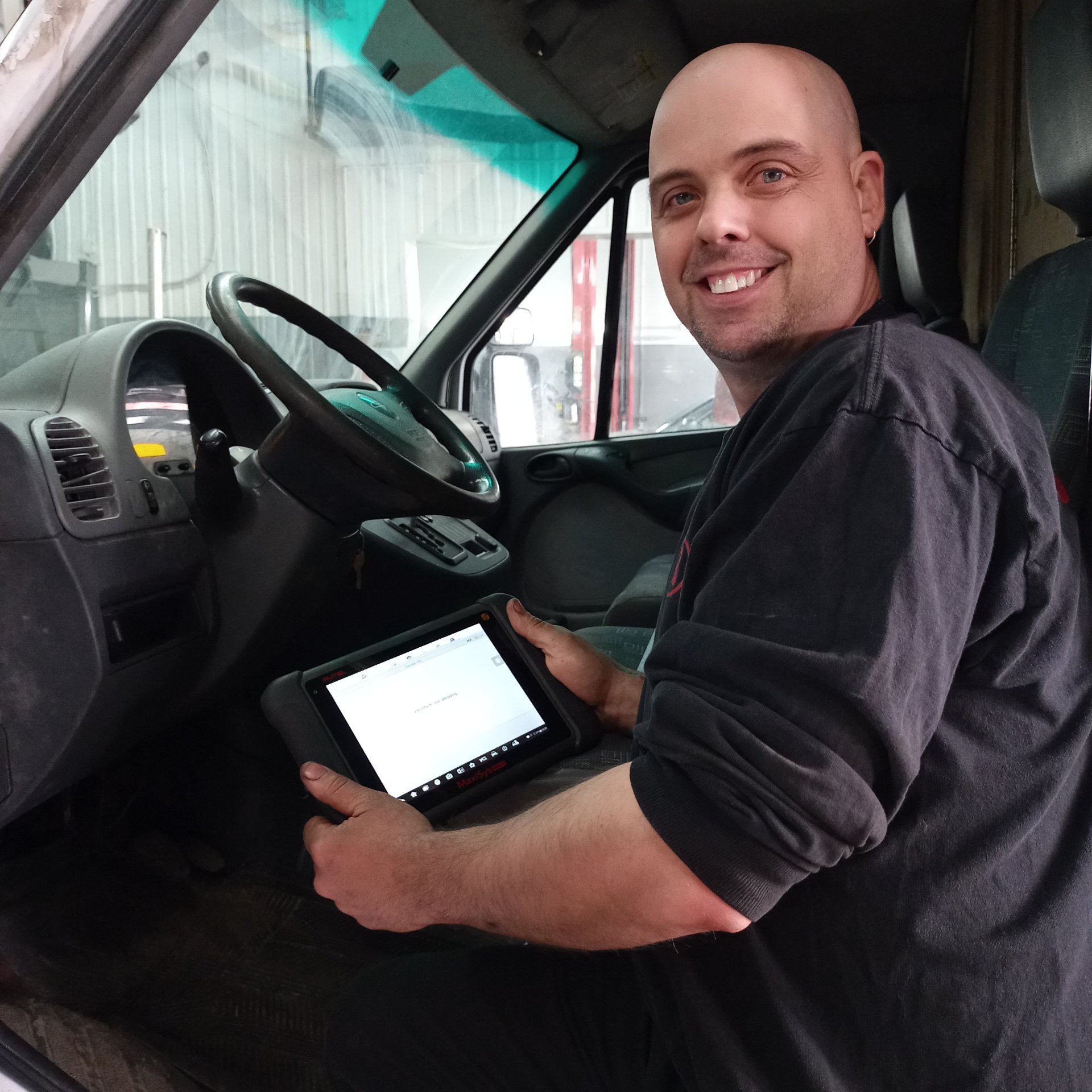 Un homme est assis sur le siège conducteur d'une camionnette tenant une tablette