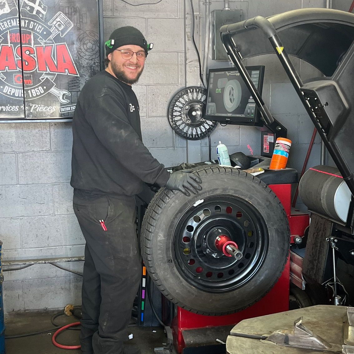 Un homme en chemise noire est assis à un bureau devant un ordinateur