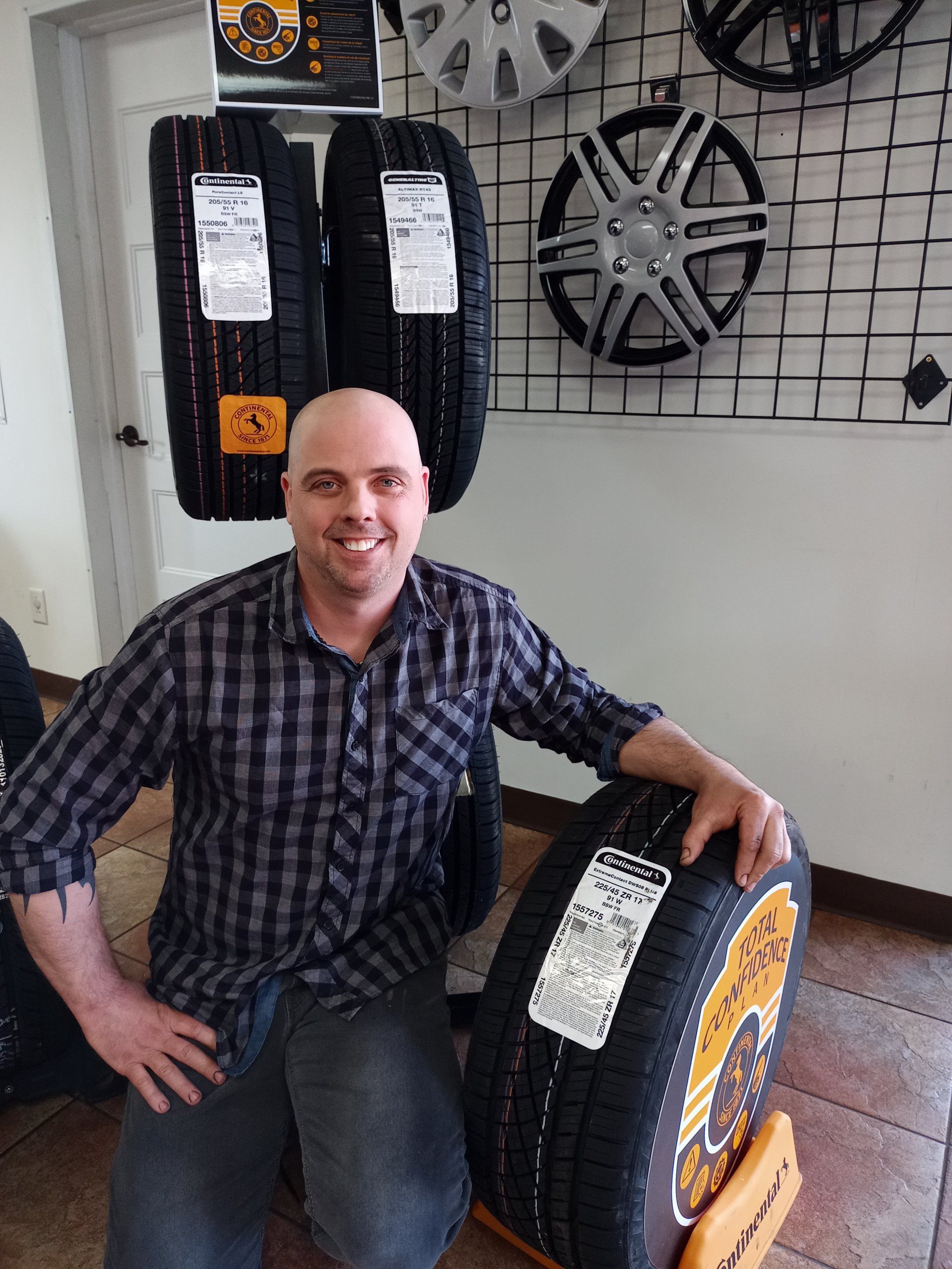 Un homme est agenouillé à côté d'un pneu dans un magasin de pneus.