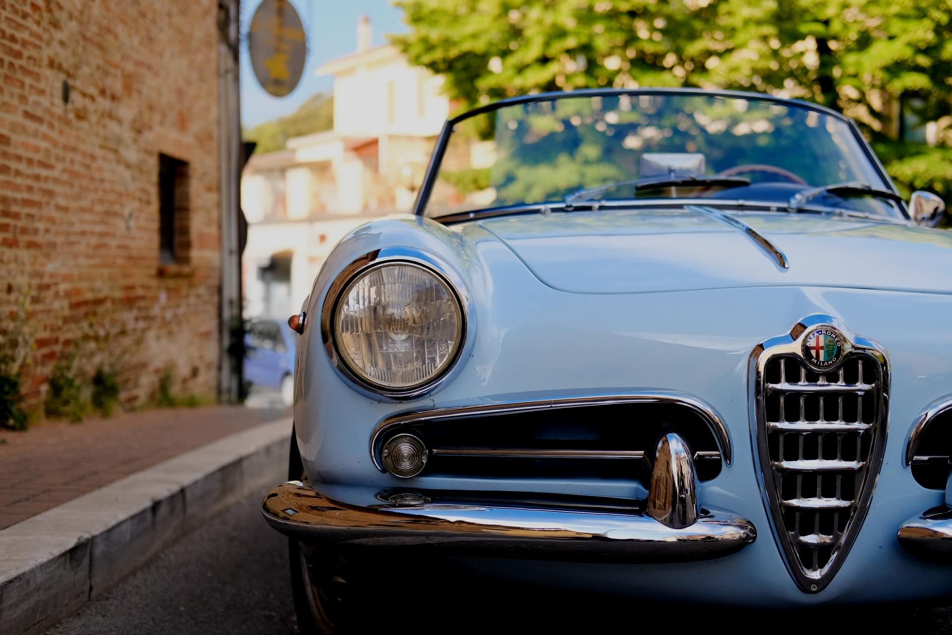 Une voiture bleue est garée sur le bord de la route à côté d'un bâtiment en briques.