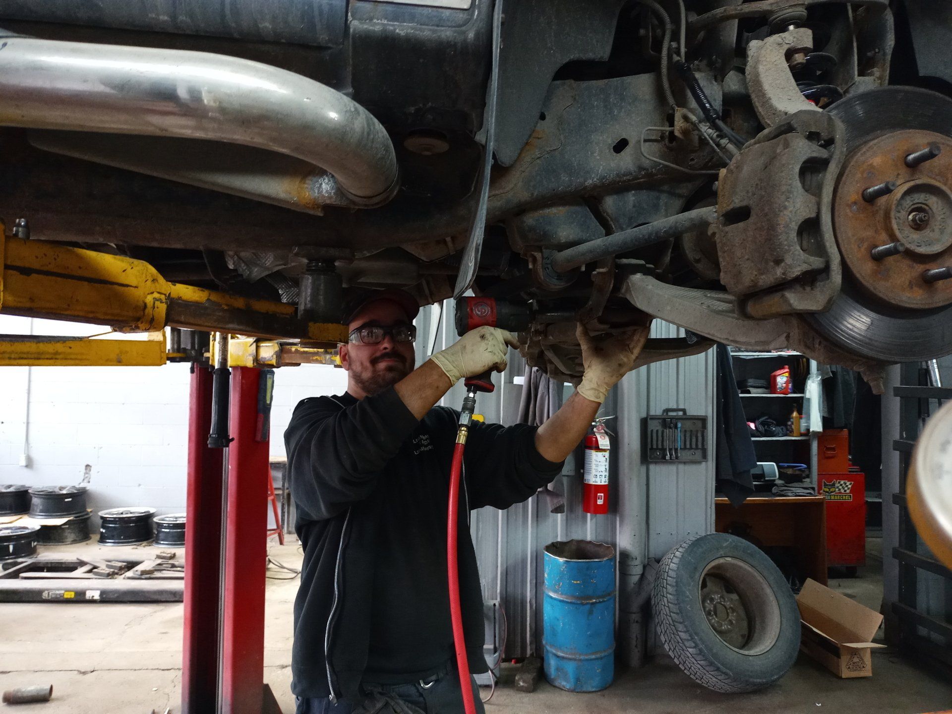 Un homme travaille sous une voiture dans un garage