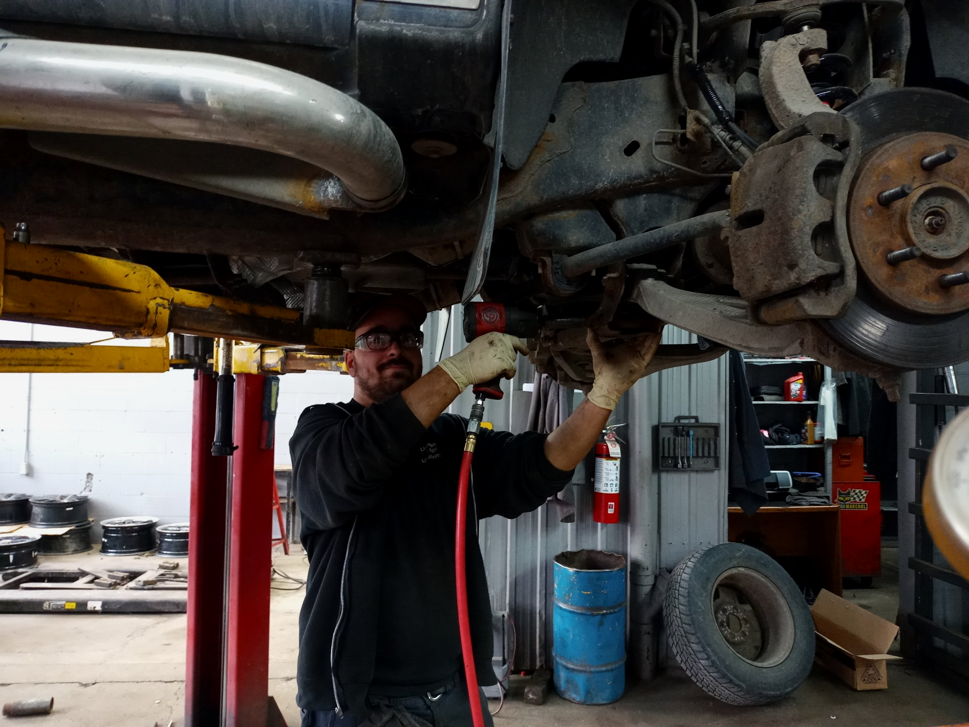 Un homme travaille sous une voiture dans un garage