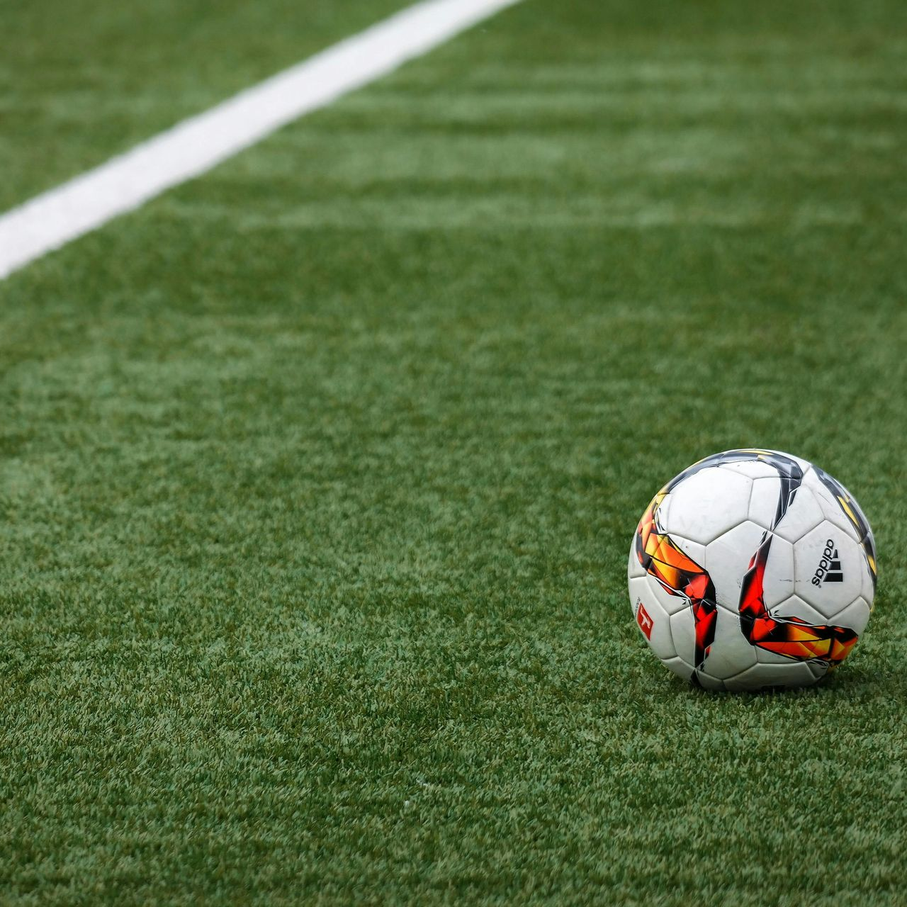 Soccer ball on a green field next to a white line.