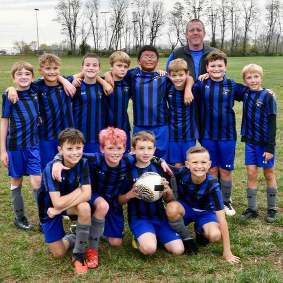 Youth soccer team in blue and black striped jerseys poses for a team photo on a green field.
