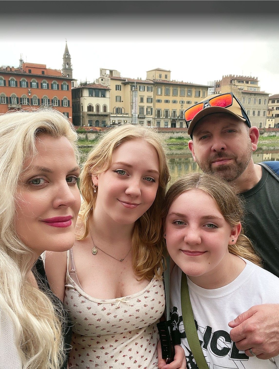 Four people posing for a selfie in front of colorful waterfront buildings.