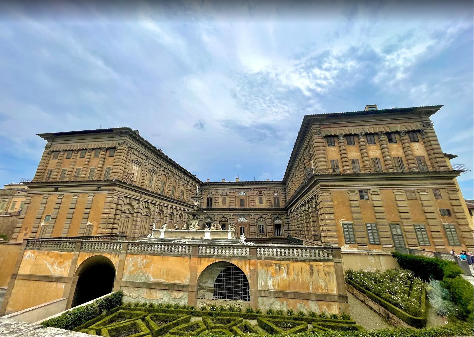 Historic stone fortress with arched entrances under a cloudy blue sky