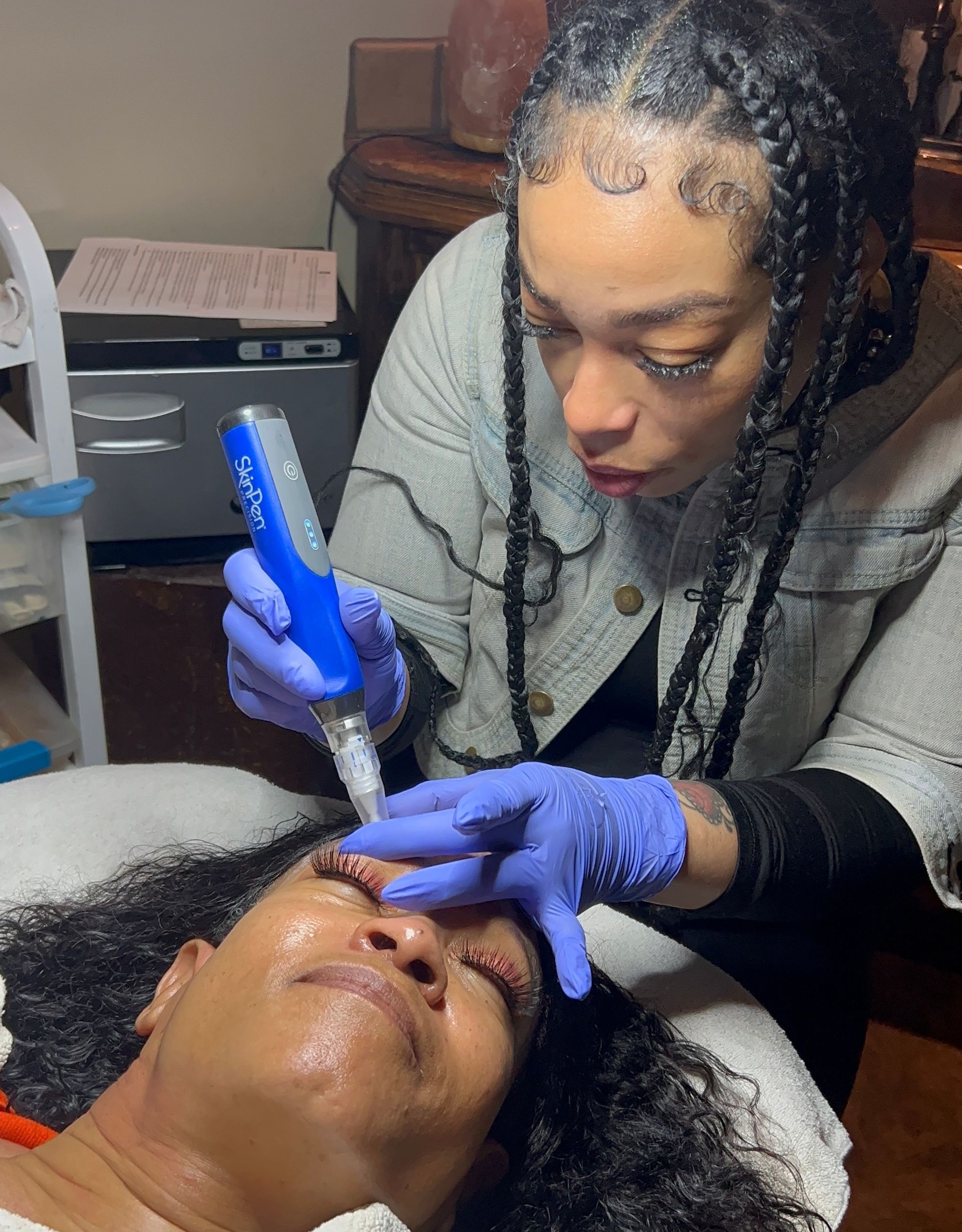 Woman with freckles applying skincare, smiling, with cream under eyes and on cheek.