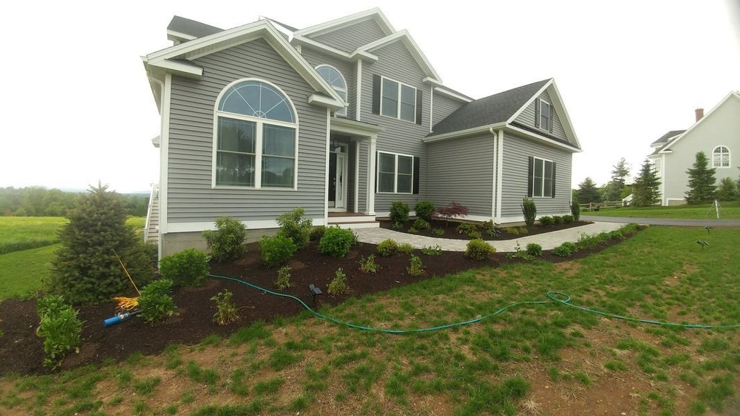 A large house is sitting on top of a lush green field.