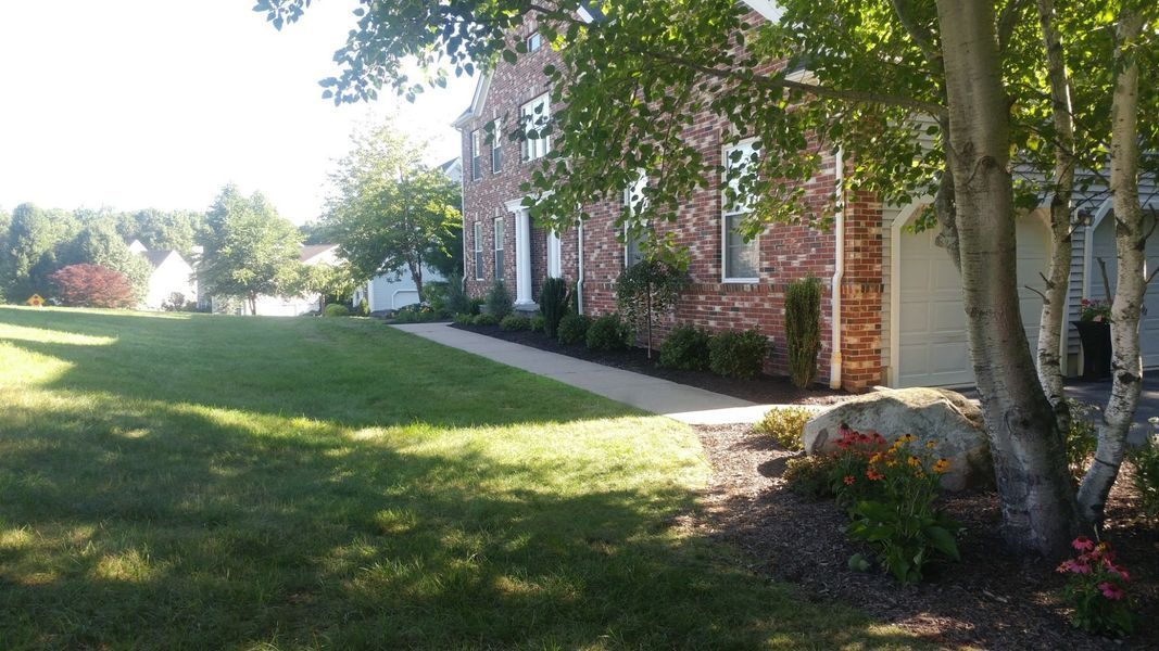 A large brick house with a large lawn in front of it.
