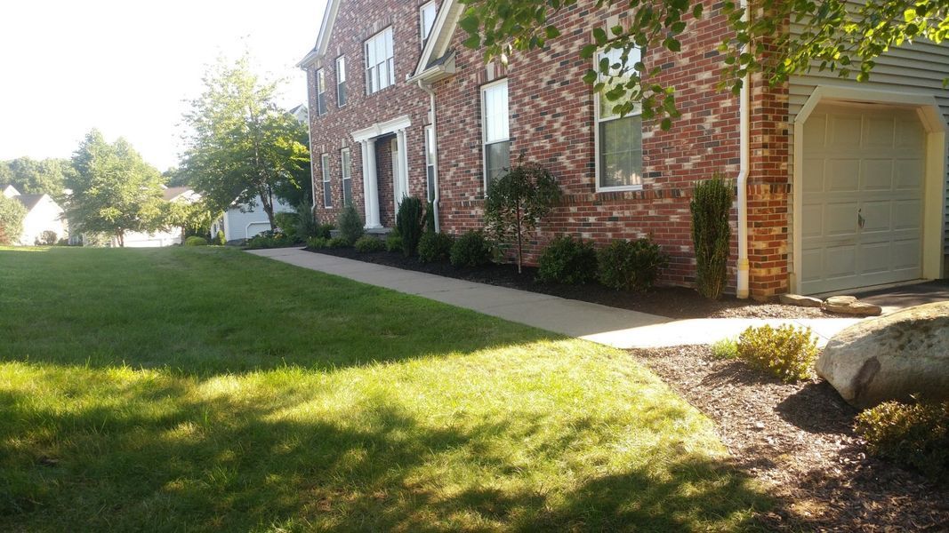 A large brick house with a large lawn in front of it.