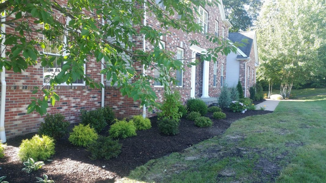 A brick house with a lush green yard in front of it.